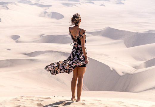 woman wearing black and multicolored floral sleeveless dress standing on desert during daytime