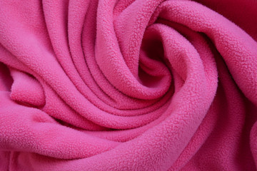 Fototapeta na wymiar Fabric of pink color woolen clothes background in spiral shape with waves.