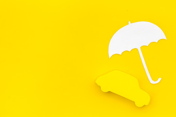Car insurance concept with car and umbrella toys on yellow background top view mockup