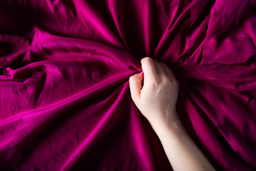 Woman hand on the silk bedding, sex and orgasm concept