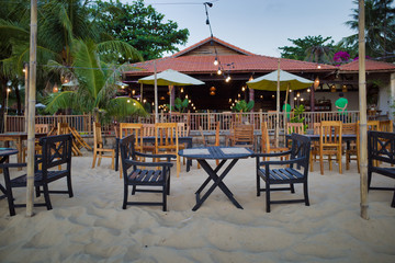 Phu Quoc, Vietnam - March 27, 2019: table and chairs in front of the beach restaurant with waiters in background