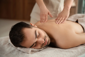 Fototapeta na wymiar Handsome man receiving back massage in spa salon