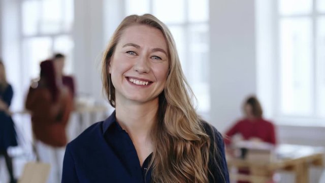Close-up portrait of happy professional female boss with blond hair in formal clothes posing at trendy modern office.