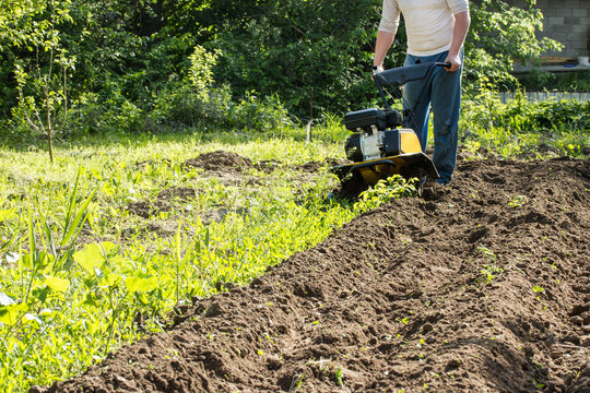 Perspective View Of Man Plowing Soil By Motor Cultivator