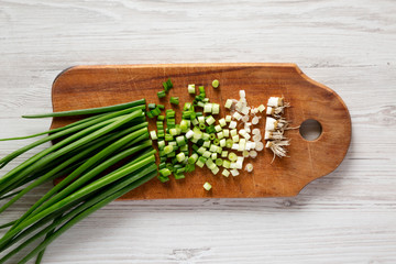 Chopped green onions on a rustic wooden board, top view. Overhead, flat lay, from above.