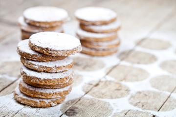 Fresh baked oat cookies with sugar powder on rustic wooden table background.