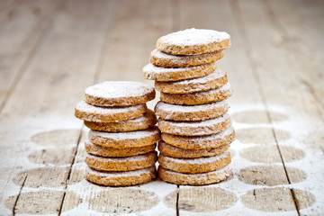Fresh oat cookies stacks with sugar powder closeup on rustic wooden table.