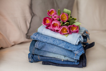 Close-up. A bouquet of tulips lying on a pile of jeans. Clothing.