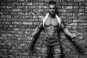 Fototapeta na wymiar Portrait of strong healthy handsome Athletic Man Fitness Model posing near Brick wall