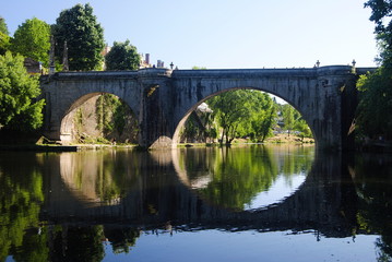 Fototapeta na wymiar Ponte de pedra antiga reflectida no rio, cidade de Amarante no norte de Portugal