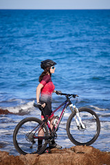 Fototapeta na wymiar female cyclist with mountain bike on the coast