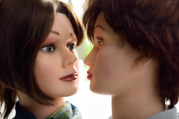 Two female mannequin heads facing each other closely about to kiss