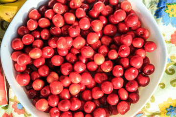 top view on deep white bowl full of fresh red cherries