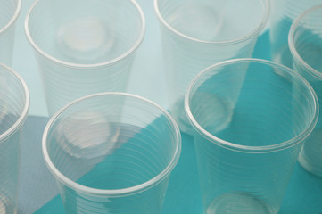 Disposable plastic cups on a blue and white background. Concept of plastic pollution of environment.