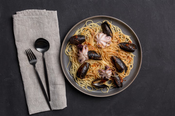 Italian pasta with octopus and mussels on gray background