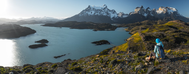 Woman hiker sits on the rock and enjoys spectacular view (from Mirador Condor) of the snow caped...