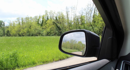 Fototapeta na wymiar Specchio retrovisore dell'auto in campagna in primavera