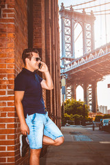 Businessman model talking on his cell phone with Manhattan Bridge in background