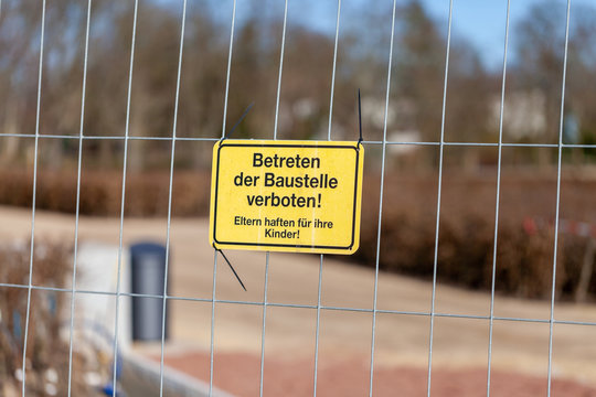 German construction side sign on a fence. Betreten der Baustelle verboten. Eltern haften für ihre Kinder, means no Trespassing. Parents are responsible for their children.