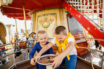 little children brother and sister having fun on the carousel