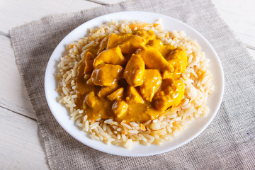 Rice with chicken curry sauce with cashew on white wooden background.