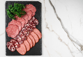 Antipasto platter cold meat with prosciutto, sausage, salami on slate stone board over marble...