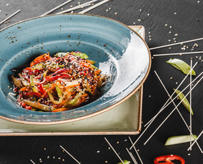 Pasta spaghetti with sauce, stew vegetables and seeds in plate on dark stone table.Vegetarian noodles, Italian food.
