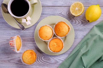 Lemon muffins with coffee on a white wooden table