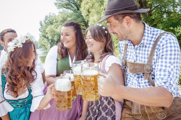 Five friends, men and women, having fun on Bavarian RIver and clinking glasses with beer