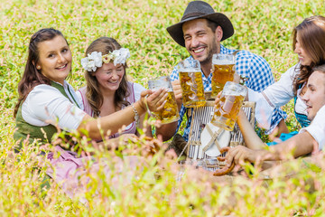 Five friends having fun on Bavarian RIver and clinking glasses with Oktoberfest beer