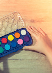 Hand holding a watercolor paint box on  wooden background