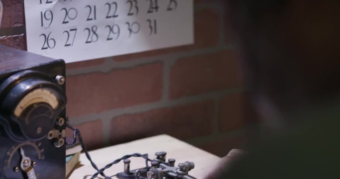 Scene tilts from a 1940s spy to the transmitting of messages via Morse Code on radio via code key.