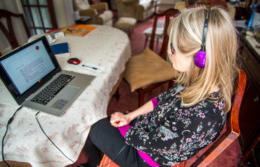 Woman listening to webinar on her laptop,wearing headphones