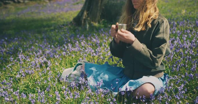 Young woman drinking coffee in a meadow