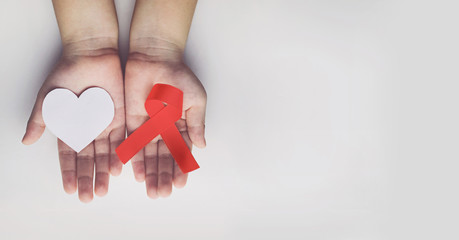 Kid hands holding red AIDS awareness ribbon. Aids Awareness