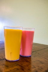 Mango Lassi and a Rose Lassi Sitting Side by Side on a Wood Table at an Indian Restaurant