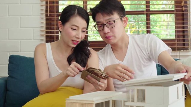 Asian couple reviewing house model for their new house project, selecting wall colour, planning for interior decoration
