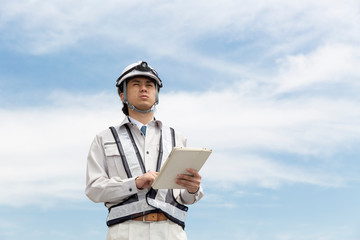 タブレットを持つ施工管理の男性　青空背景