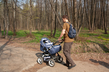 Young father walks with a baby carriage in the Park