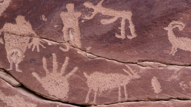 Panning over petroglyph carving of people and hands in rock wall in Nine Mile Canyon in Utah.