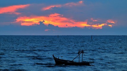 Small fishing boat parked in the sea at sunset