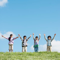 草原で両手を挙げる小学生