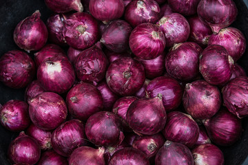A pile of red onions. Onion used in cooking with a pungent taste and smell. selective focus.
