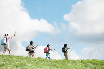 風車を持ち草原を歩く小学生の後姿
