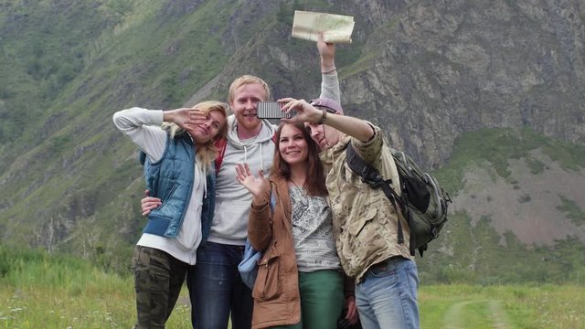 friends travelers with backpacks do selfie on the phone in the mountains. A group of tourists take pictures on the phone in the background of the mountains. tourists are photographed against the