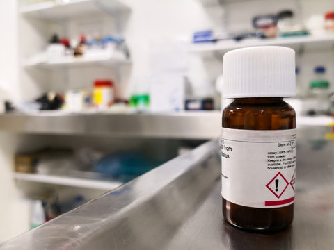 Amber bottle for storage of a chemical substance in a scientific laboratory. Symbols of attention and danger on the label. Hazardous material. Colorful background with science concept.