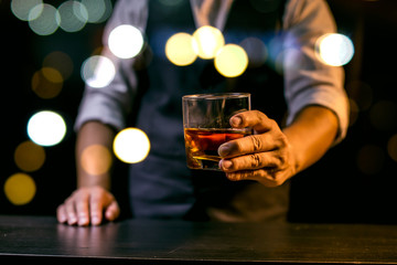 Barman pouring whiskey glass on beautiful bokeh background