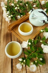 Jasmine tea.Green tea with jasmine flowers. teapot and two cups of tea, jasmine branches on a wooden board background.Organic Natural Herbal Bio Tea
