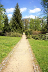 Palace garden with a small river and blooming rhododendrons. Landscape architecture around a small palace in Losiny Velke, Czech Republic. 