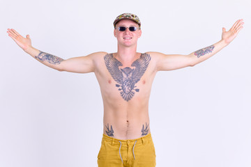 Fototapeta premium Happy young handsome shirtless man with tattoos raising arms
